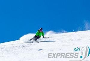 Woman skier at high speed in deep snow in a turn raises the snow dust